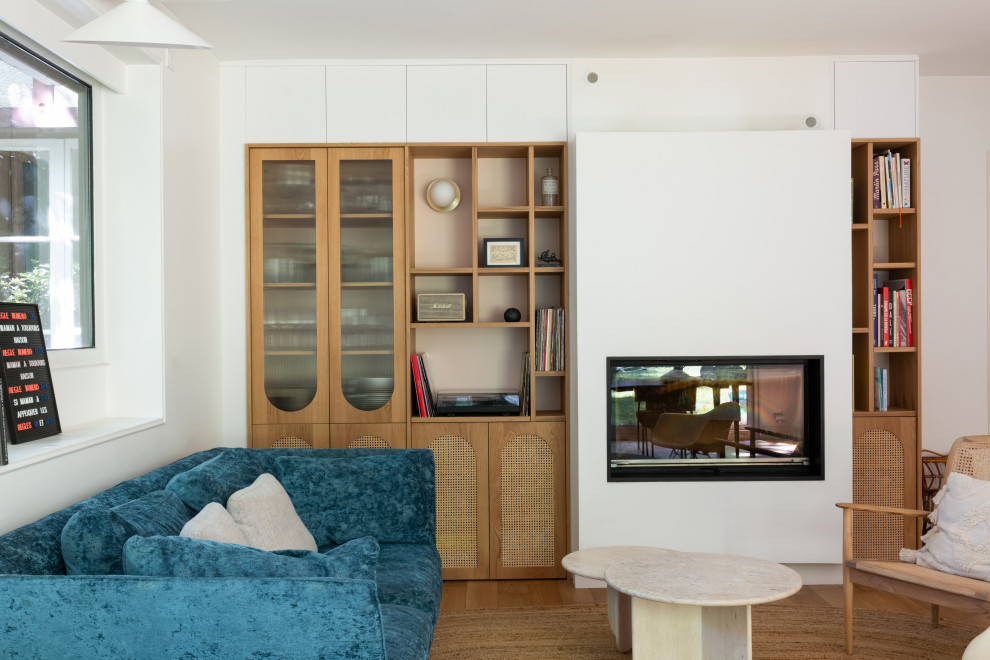 Foto di un soggiorno minimalista di medie dimensioni e chiuso con libreria, pareti bianche, camino classico, nessuna TV, pavimento marrone e parquet chiaro