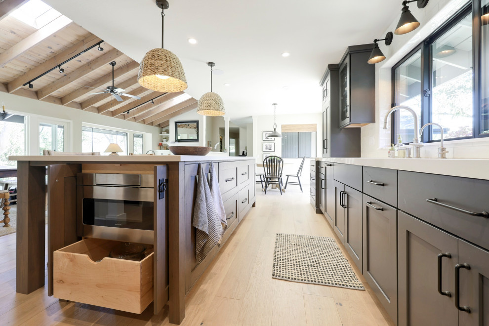 Inspiration for a mid-sized transitional l-shaped laminate floor open concept kitchen remodel with a double-bowl sink, flat-panel cabinets, gray cabinets, quartz countertops, white backsplash, ceramic backsplash, stainless steel appliances, an island and white countertops
