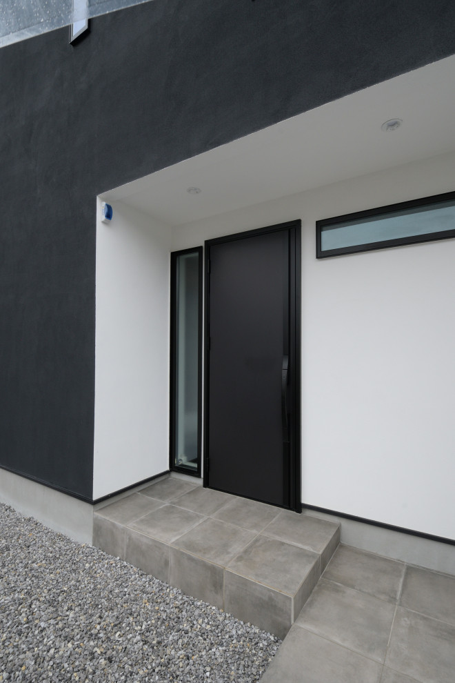 На фото: входная дверь в стиле модернизм с белыми стенами, бетонным полом, одностворчатой входной дверью и черной входной дверью