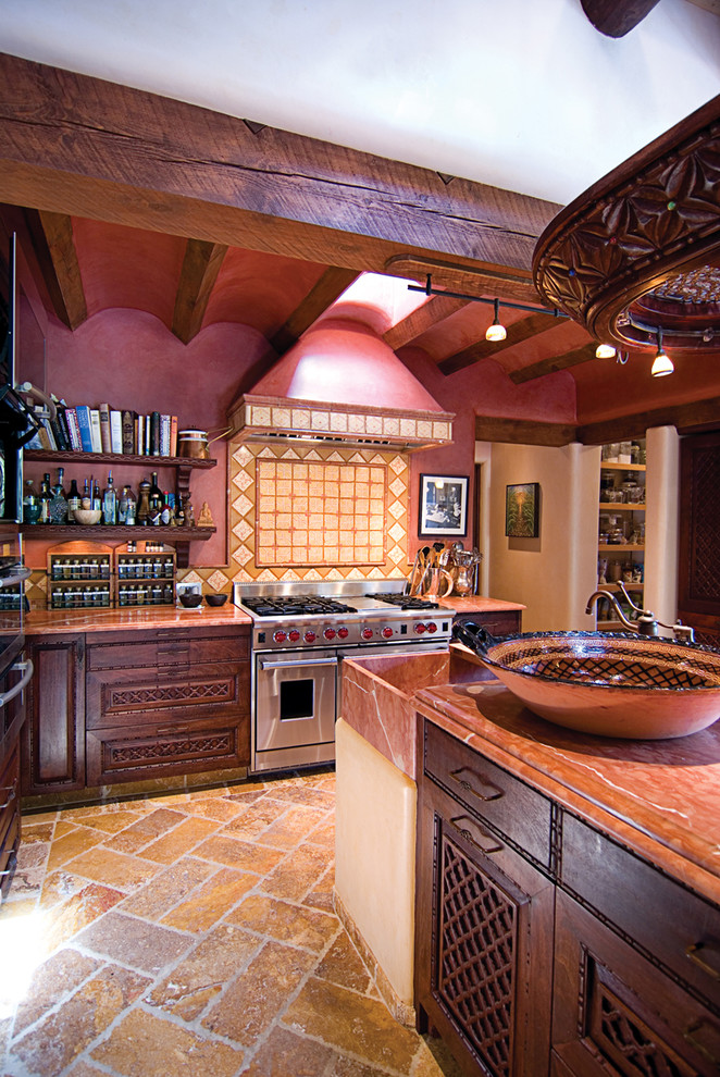 This is an example of a mid-sized mediterranean u-shaped eat-in kitchen in Albuquerque with a single-bowl sink, recessed-panel cabinets, dark wood cabinets, marble benchtops, multi-coloured splashback, terra-cotta splashback, stainless steel appliances, travertine floors and with island.
