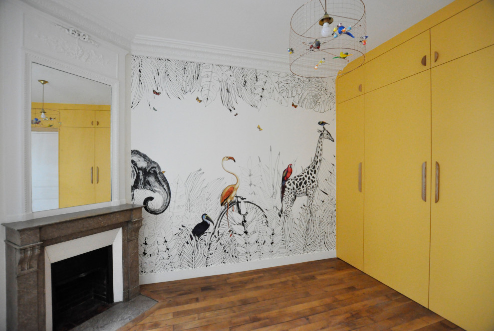 This is an example of a medium sized contemporary gender neutral toddler’s room in Paris with yellow walls, dark hardwood flooring, wallpapered walls and beige floors.