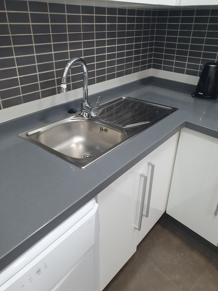 Photo of a medium sized modern grey and white l-shaped enclosed kitchen in Malaga with a belfast sink, shaker cabinets, white cabinets, engineered stone countertops, grey splashback, mosaic tiled splashback, stainless steel appliances, ceramic flooring, no island, grey floors and grey worktops.