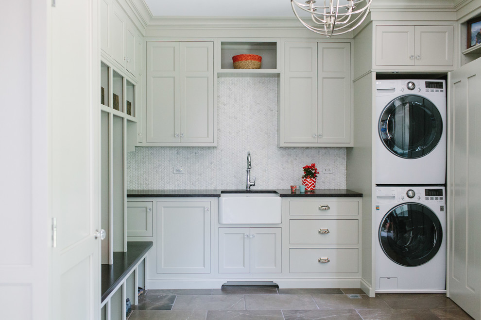 Design ideas for a large transitional l-shaped dedicated laundry room in Chicago with a farmhouse sink, recessed-panel cabinets, white cabinets, solid surface benchtops, white walls, marble floors, a concealed washer and dryer and grey floor.