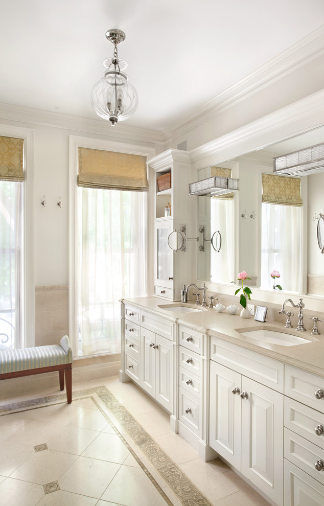 Inspiration for a large traditional master bathroom in New York with an undermount sink, recessed-panel cabinets, white cabinets, limestone benchtops, beige tile, stone slab, beige walls and limestone floors.