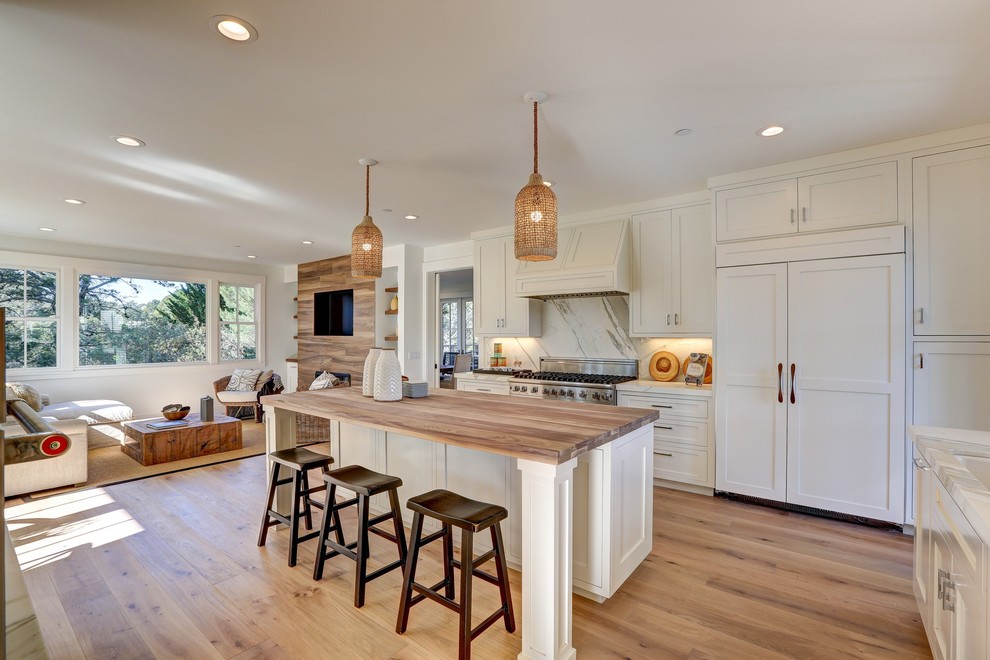 Transitional open plan kitchen in San Francisco with shaker cabinets, white cabinets, white splashback, stainless steel appliances, light hardwood floors and with island.