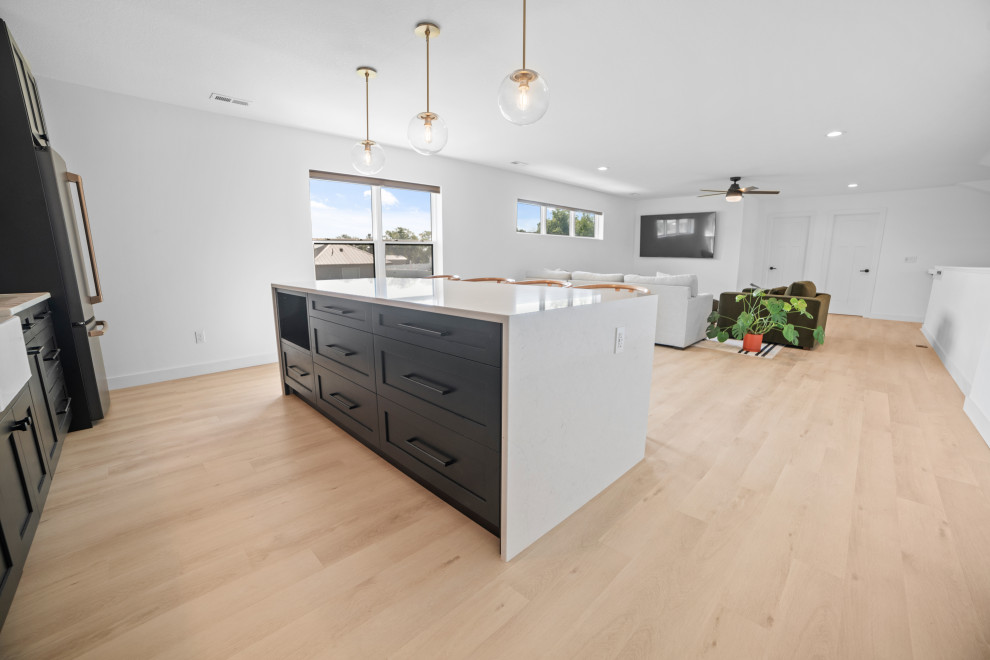 Inspiration for a large scandinavian l-shaped seated home bar in Cedar Rapids with a drop-in sink, beaded inset cabinets, green cabinets, limestone benchtops, white splashback, ceramic splashback, vinyl floors, beige floor and white benchtop.