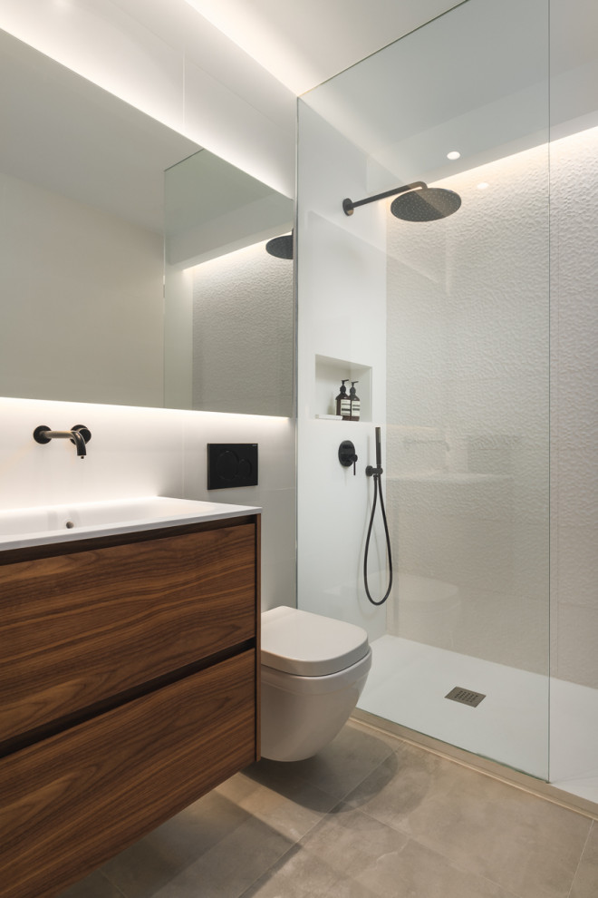 Photo of a medium sized modern ensuite wet room bathroom in Madrid with flat-panel cabinets, medium wood cabinets, a one-piece toilet, white tiles, ceramic tiles, white walls, ceramic flooring, an integrated sink, engineered stone worktops, grey floors, an open shower, white worktops, an enclosed toilet, a single sink and a floating vanity unit.