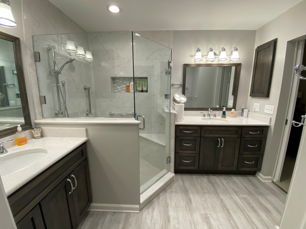 Inspiration for a mid-sized transitional master bathroom in Cleveland with shaker cabinets, grey cabinets, a corner shower, a two-piece toilet, white tile, porcelain tile, grey walls, vinyl floors, an undermount sink, engineered quartz benchtops, grey floor, a hinged shower door, white benchtops, a shower seat, a double vanity and a built-in vanity.