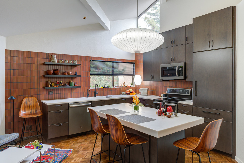 Design ideas for a mid-sized midcentury l-shaped eat-in kitchen in San Francisco with an undermount sink, flat-panel cabinets, dark wood cabinets, brown splashback, stainless steel appliances, medium hardwood floors, with island, brown floor and white benchtop.