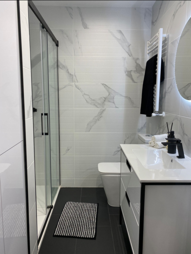 This is an example of a medium sized modern ensuite bathroom in Madrid with freestanding cabinets, white cabinets, a freestanding bath, an alcove shower, a one-piece toilet, black and white tiles, porcelain tiles, multi-coloured walls, porcelain flooring, a built-in sink, marble worktops, black floors, a sliding door, white worktops, an enclosed toilet, a single sink and a freestanding vanity unit.