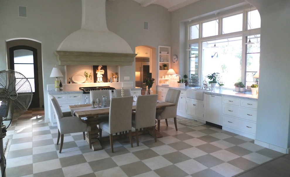 Photo of a large transitional l-shaped eat-in kitchen in Sacramento with a farmhouse sink, white cabinets, white splashback, stone slab splashback, stainless steel appliances, ceramic floors, with island, shaker cabinets and marble benchtops.