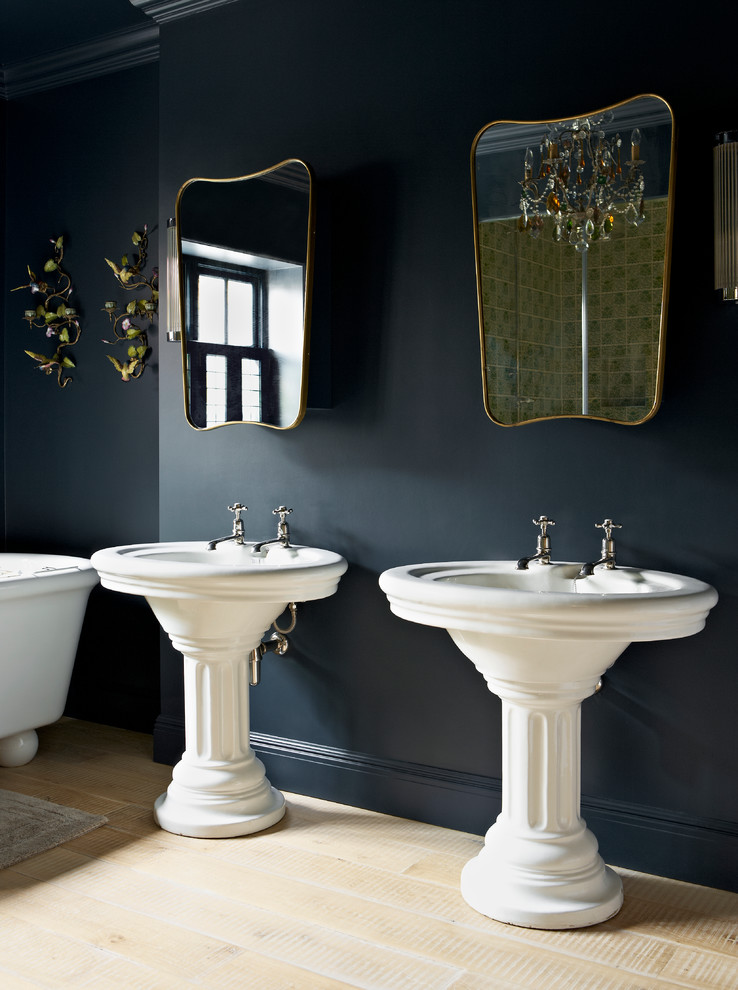 Photo of a traditional bathroom in London with a pedestal sink, black walls and light hardwood floors.