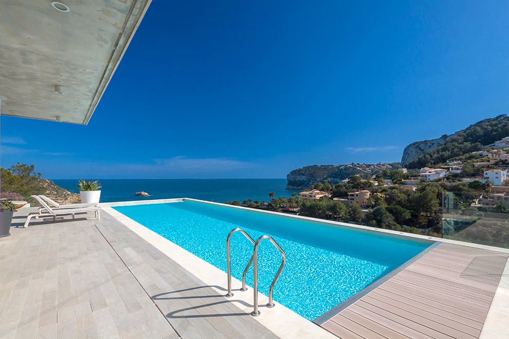 Photo of a large contemporary backyard rectangular lap pool in Alicante-Costa Blanca with a water feature and decking.