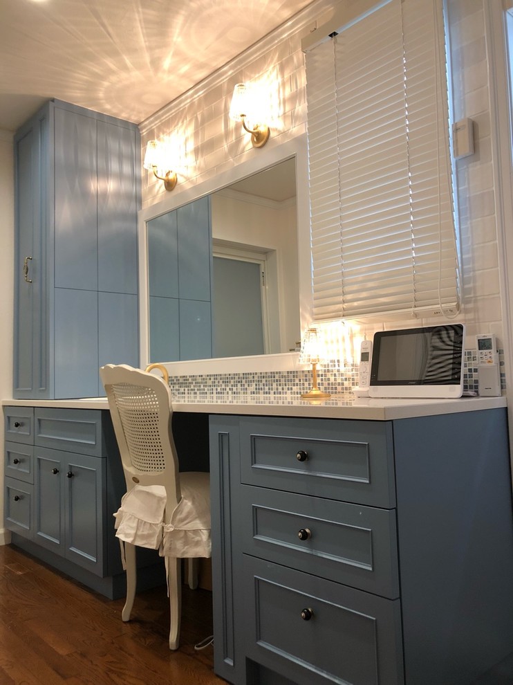 京都にあるトラディショナルスタイルのおしゃれなトイレ・洗面所 (家具調キャビネット、青いキャビネット、一体型トイレ	、マルチカラーのタイル、モザイクタイル、白い壁、無垢フローリング、一体型シンク、人工大理石カウンター、茶色い床、白い洗面カウンター) の写真