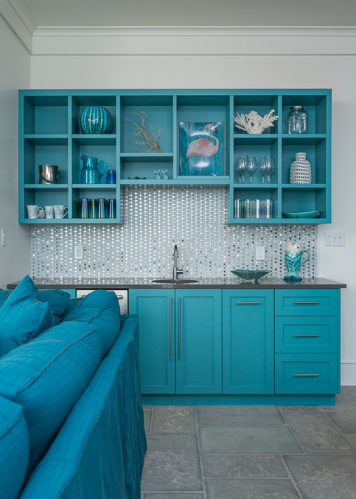 This is an example of a mid-sized beach style single-wall wet bar in Miami with an undermount sink, shaker cabinets, blue cabinets, solid surface benchtops, grey splashback, glass tile splashback and concrete floors.
