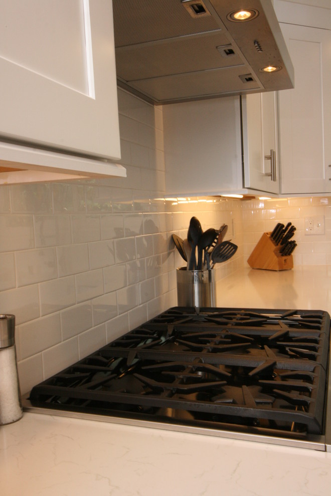 Example of a large transitional u-shaped dark wood floor eat-in kitchen design in Orange County with a farmhouse sink, shaker cabinets, white cabinets, quartz countertops, white backsplash, ceramic backsplash, stainless steel appliances and an island