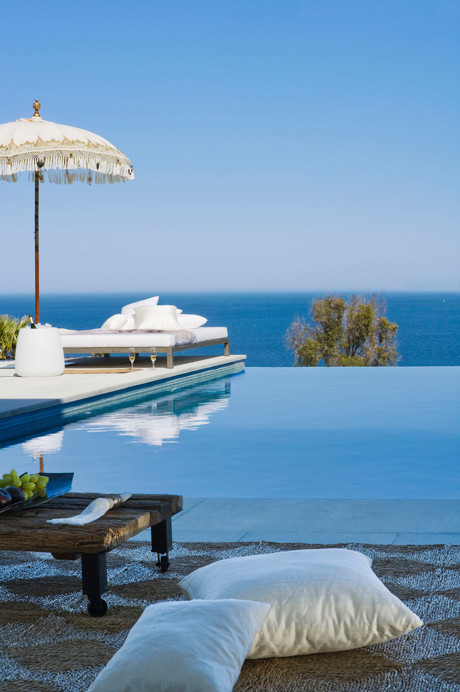 This is an example of a beach style rectangular infinity pool in Other.