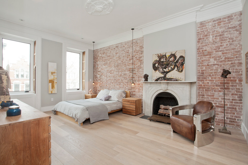Inspiration for a large scandinavian master bedroom in New York with grey walls, light hardwood floors, a standard fireplace and a stone fireplace surround.