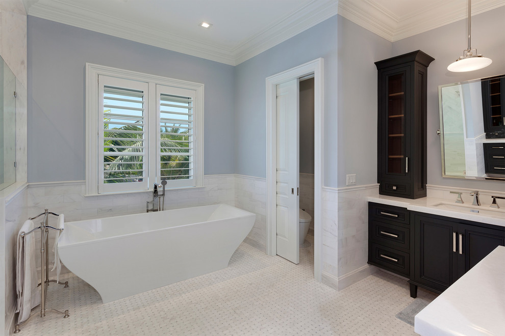 Design ideas for a mid-sized contemporary master bathroom in Miami with black cabinets, a freestanding tub, a corner shower, white walls, grey floor, a hinged shower door, white benchtops, recessed-panel cabinets, a one-piece toilet, gray tile, porcelain tile, mosaic tile floors, an undermount sink and solid surface benchtops.