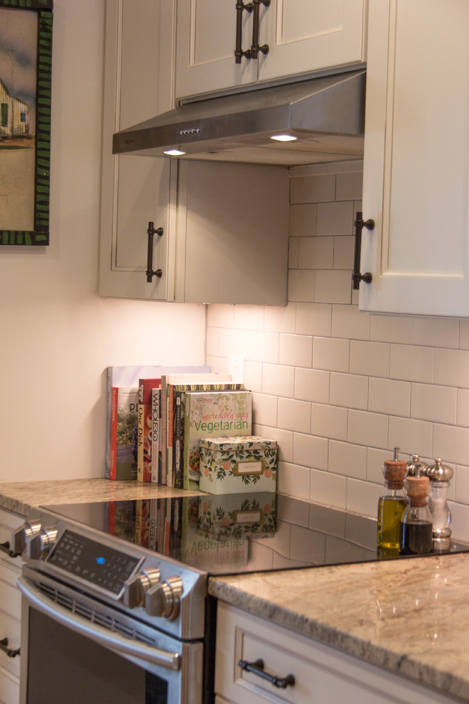 Example of a transitional medium tone wood floor kitchen design with granite countertops, subway tile backsplash and stainless steel appliances