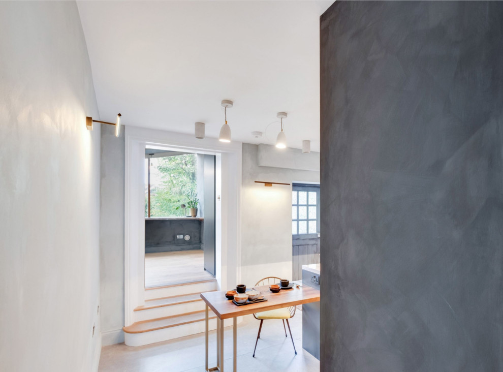 Inspiration for a mid-sized modern u-shaped eat-in kitchen in London with an integrated sink, flat-panel cabinets, black cabinets, tile benchtops, grey splashback, porcelain splashback, stainless steel appliances, porcelain floors, a peninsula, grey floor and white benchtop.