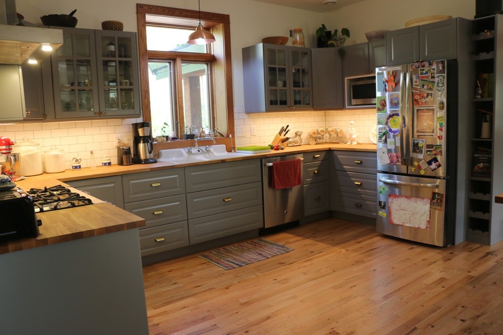 Mid-sized transitional u-shaped eat-in kitchen in Minneapolis with shaker cabinets, grey cabinets, wood benchtops, white splashback, subway tile splashback, stainless steel appliances, medium hardwood floors, with island, brown floor and brown benchtop.