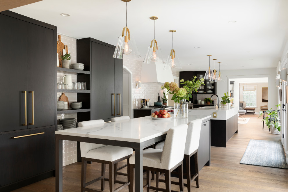 This is an example of a large transitional kitchen in Minneapolis with a single-bowl sink, flat-panel cabinets, dark wood cabinets, quartz benchtops, ceramic splashback, panelled appliances, medium hardwood floors, multiple islands and brown floor.