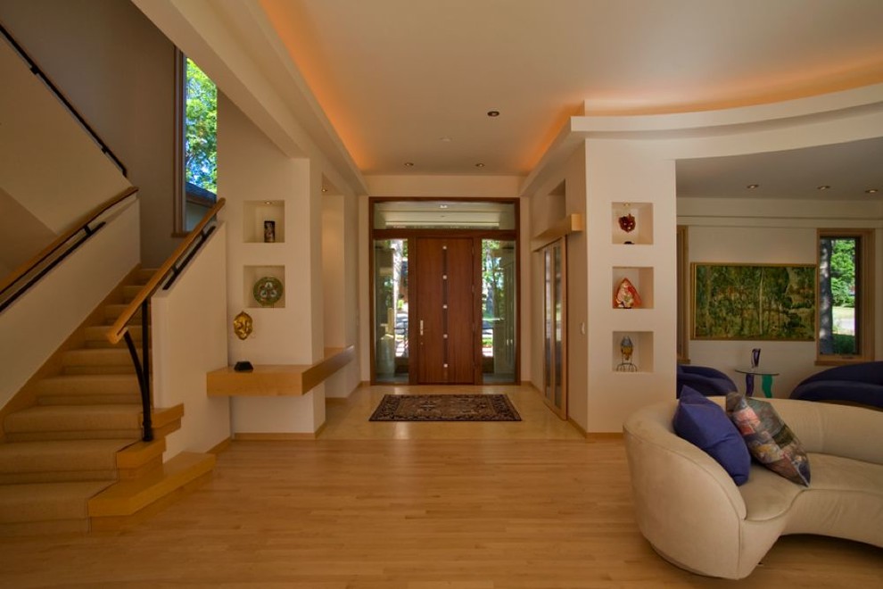 This is an example of a mid-sized contemporary foyer in Minneapolis with white walls, light hardwood floors, a single front door, a medium wood front door and beige floor.