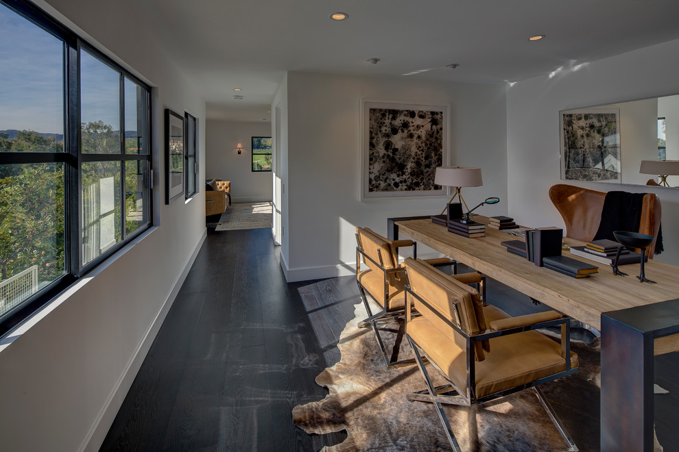 Large contemporary study room in Los Angeles with white walls, dark hardwood floors and a freestanding desk.