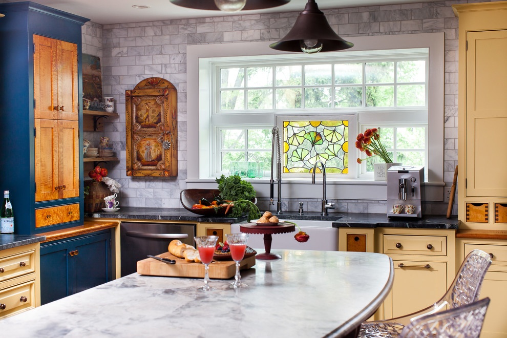 Photo of a mid-sized country l-shaped eat-in kitchen in Philadelphia with a farmhouse sink, beaded inset cabinets, yellow cabinets, white splashback, stone tile splashback and with island.