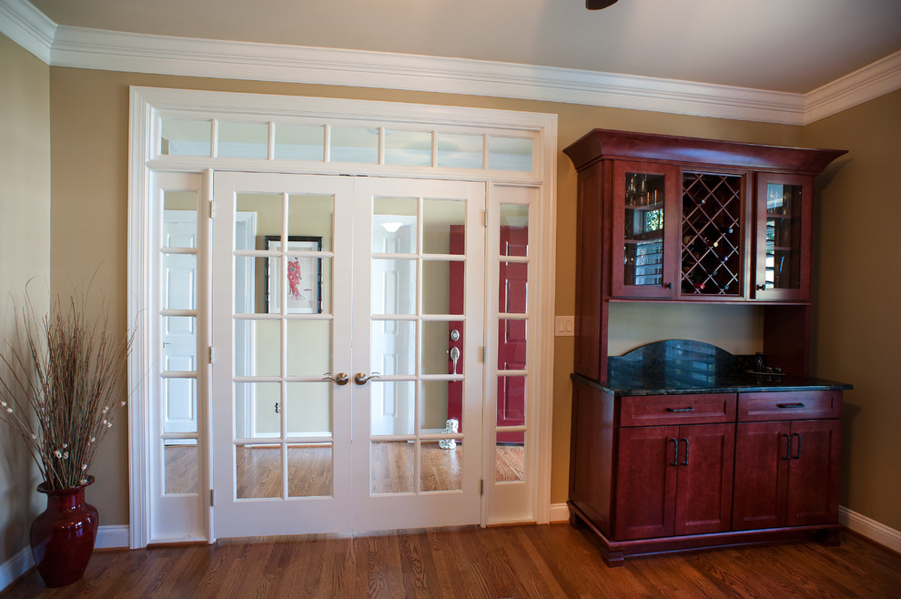 Inspiration for a mid-sized transitional l-shaped kitchen remodel in Charlotte with dark wood cabinets, granite countertops, white backsplash and an island
