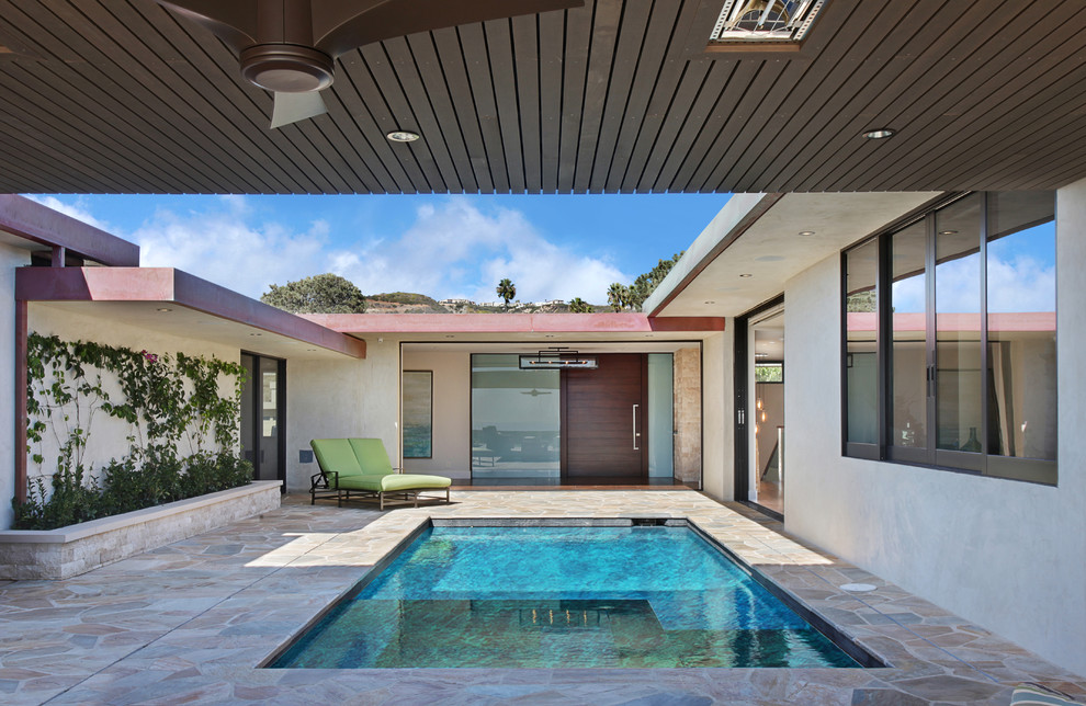 This is an example of a mid-sized modern courtyard rectangular pool in Orange County with natural stone pavers.