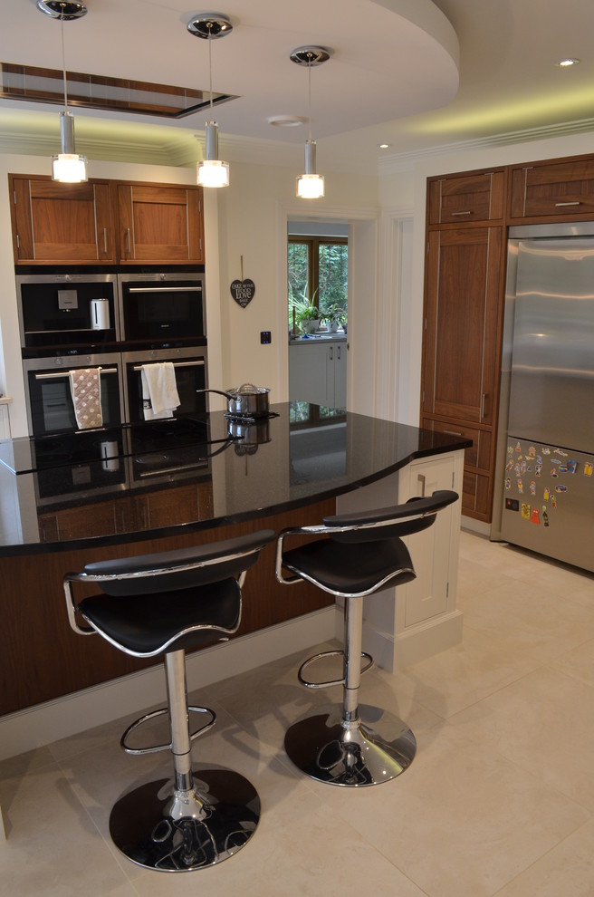 Photo of an expansive contemporary l-shaped eat-in kitchen in Hertfordshire with recessed-panel cabinets, medium wood cabinets, quartz benchtops, stainless steel appliances and with island.