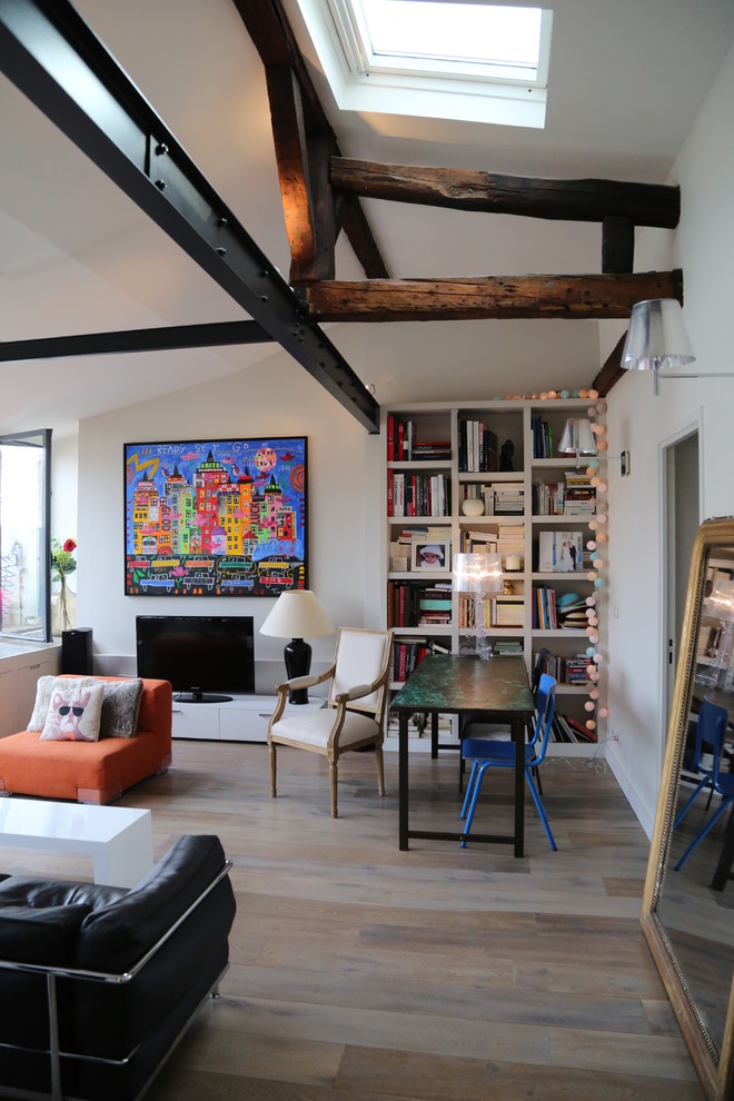 Eclectic living room in Paris with white walls, medium hardwood floors, a freestanding tv and brown floor.