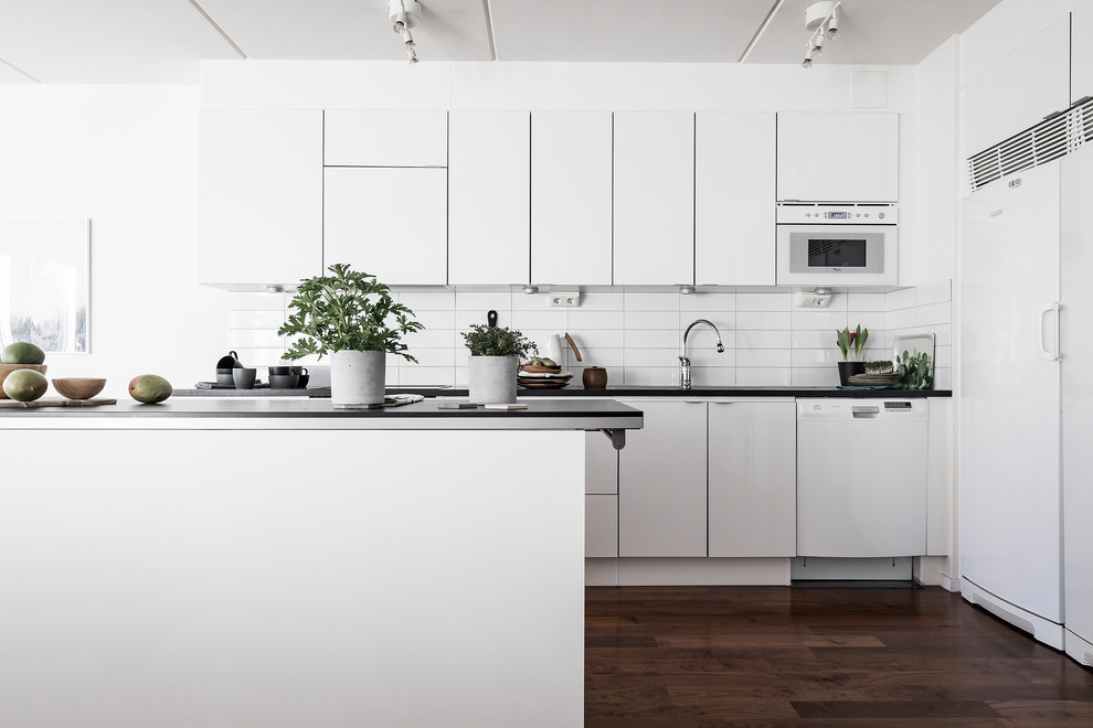 Design ideas for a mid-sized scandinavian kitchen in Stockholm with flat-panel cabinets, white cabinets, white appliances, with island, white splashback and dark hardwood floors.