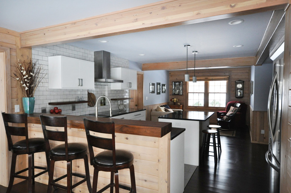 Inspiration for a mid-sized transitional l-shaped dark wood floor eat-in kitchen remodel in Grand Rapids with an undermount sink, flat-panel cabinets, white cabinets, soapstone countertops, white backsplash, subway tile backsplash, stainless steel appliances and an island