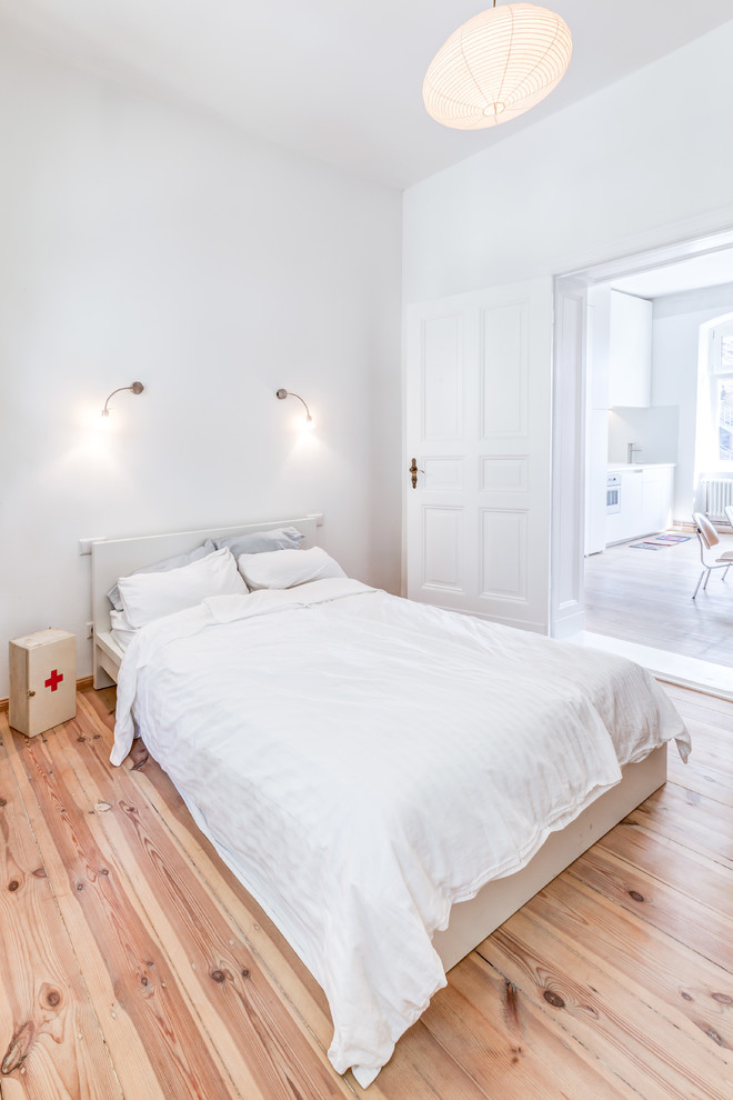 This is an example of a mid-sized scandinavian master bedroom in Berlin with white walls, light hardwood floors and no fireplace.