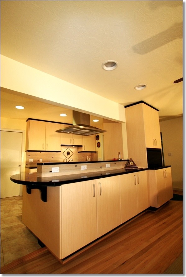 Photo of a mid-sized modern galley eat-in kitchen in Other with an undermount sink, flat-panel cabinets, light wood cabinets, quartz benchtops, beige splashback, porcelain splashback, stainless steel appliances and porcelain floors.