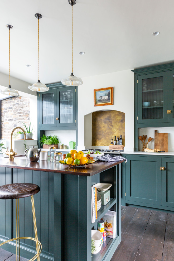 Design ideas for a mid-sized eclectic single-wall eat-in kitchen in London with a farmhouse sink, shaker cabinets, green cabinets, quartzite benchtops, metallic splashback, marble splashback, black appliances, dark hardwood floors, with island, brown floor and white benchtop.