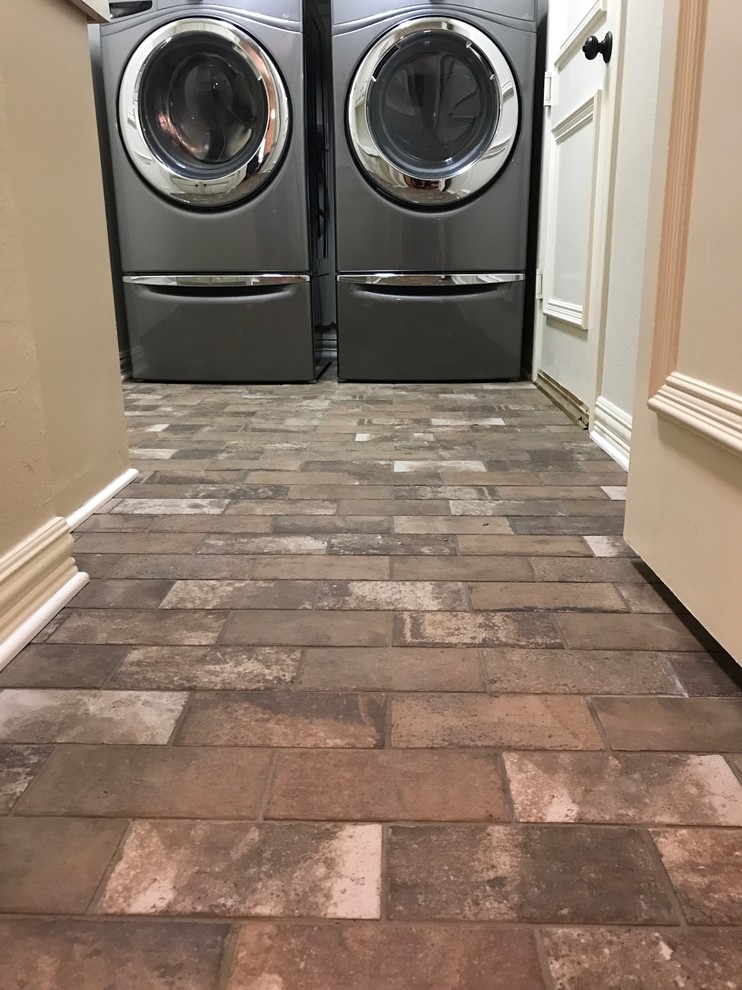 Photo of a mid-sized traditional galley dedicated laundry room in Dallas with beige walls, brick floors, a side-by-side washer and dryer and brown floor.