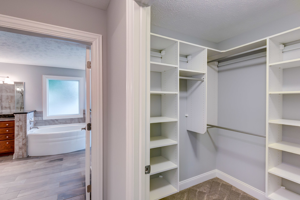 This is an example of a mid-sized transitional women's walk-in wardrobe in Cleveland with white cabinets and carpet.