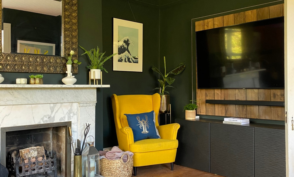 This is an example of a large traditional enclosed living room in Sussex with green walls, medium hardwood floors, a standard fireplace, a stone fireplace surround, a built-in media wall and wallpaper.