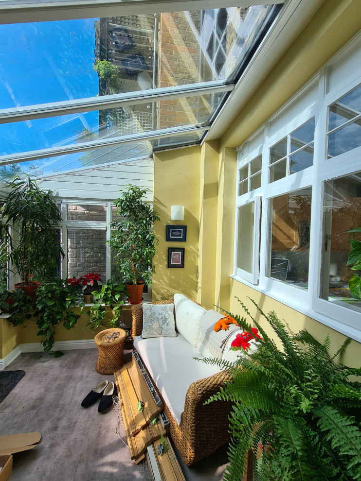 Mid-sized traditional backyard screened-in verandah in London with tile, a roof extension and glass railing.