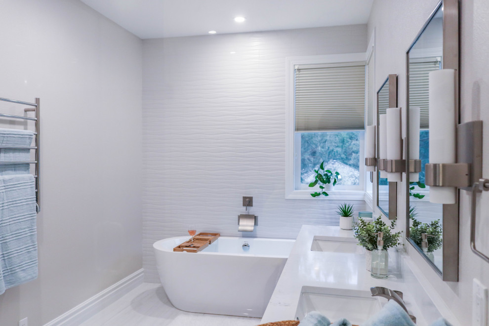 Photo of a contemporary master bathroom in Seattle with furniture-like cabinets, dark wood cabinets, a freestanding tub, a corner shower, a one-piece toilet, white tile, ceramic tile, white walls, ceramic floors, an undermount sink, marble benchtops, white floor, a hinged shower door, white benchtops, a shower seat, a double vanity and a freestanding vanity.
