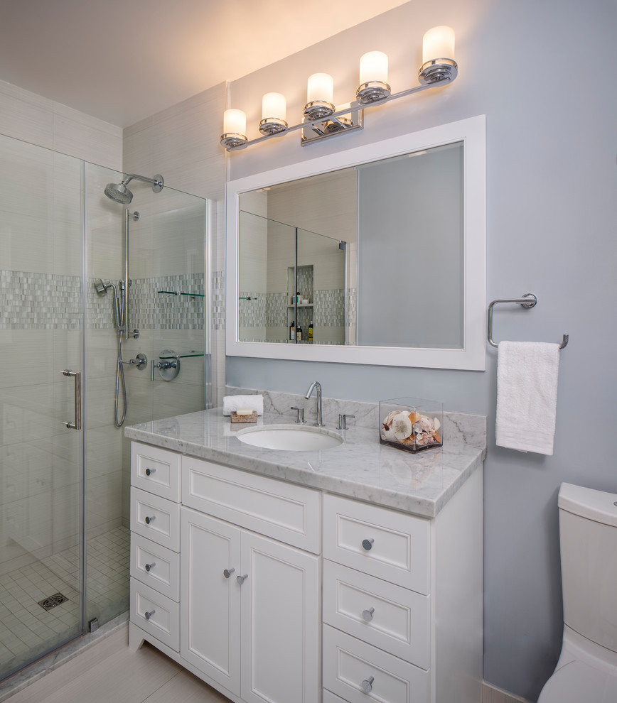 Inspiration for a small transitional master bathroom in Miami with shaker cabinets, white cabinets, an alcove shower, a two-piece toilet, white tile, porcelain tile, grey walls, porcelain floors, an undermount sink, marble benchtops, white floor and a hinged shower door.