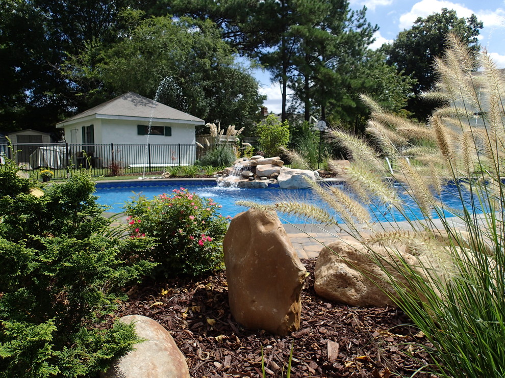Photo of a mid-sized contemporary backyard custom-shaped pool in Other with a water feature and natural stone pavers.