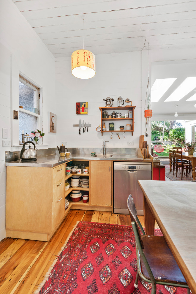 Eclectic kitchen in Wellington with an integrated sink, flat-panel cabinets, medium wood cabinets, stainless steel benchtops, stainless steel appliances, medium hardwood floors, with island, brown floor and grey benchtop.