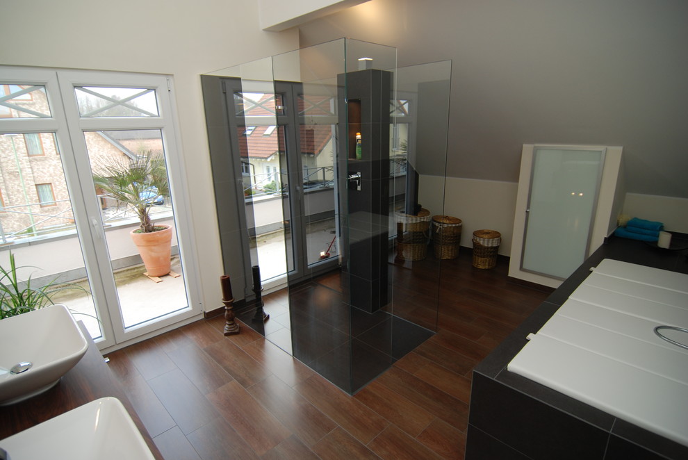 Badezimmer mit Aufsatzwaschbecken, Glasfronten, Einbaubadewanne, bodengleicher Dusche, Wandtoilette, grauen Fliesen, Steinfliesen und Porzellan-Bodenfliesen in Dusseldorf