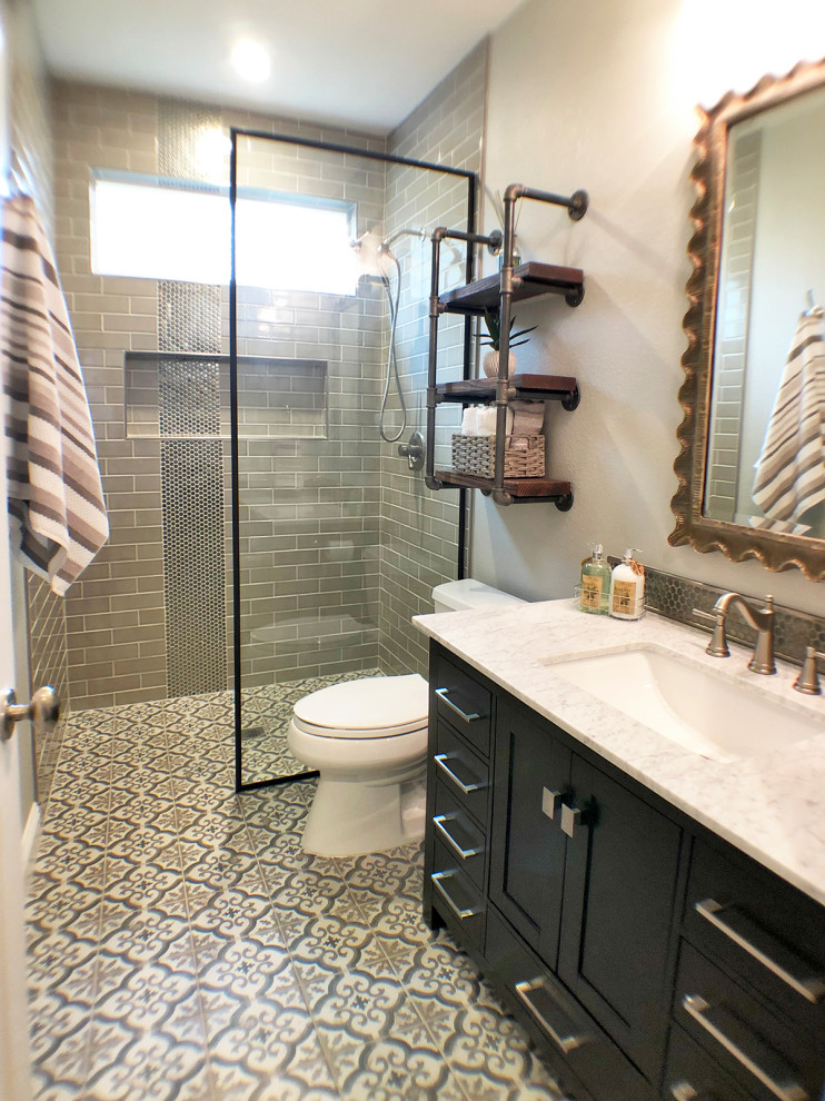 Design ideas for a small industrial bathroom in Dallas with shaker cabinets, black cabinets, a curbless shower, a one-piece toilet, brown tile, subway tile, grey walls, porcelain floors, an undermount sink, marble benchtops, multi-coloured floor, an open shower and white benchtops.
