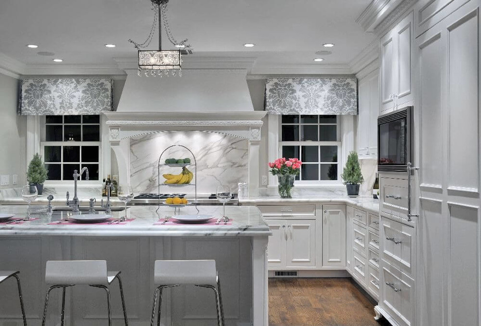 Example of a mid-sized transitional l-shaped laminate floor eat-in kitchen design with recessed-panel cabinets, white cabinets, quartzite countertops, gray backsplash and an island